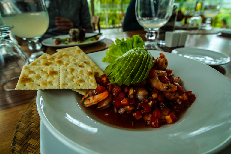 In dem Restaurant Mengelas in Guatemala wurde auf einem weißen Teller, neben Kräcker und Salat das Gericht Ceviche, Gemüse mit Meeresfrüchte, serviert.