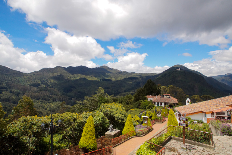 Trotz Wolken wirft die Sonne Licht auf Kolumbiens Monserrate und seinen grün bewachsenen Hügeln.