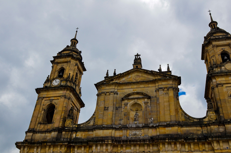 The old buildings at Bogotá Plaza de Bolívar are yellow with two towers and have tinted the edges black over the years.