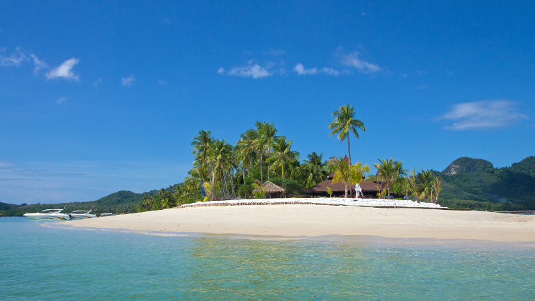 Die Landzunge des Sivalai Beach auf Koh Mook ist von türkisblauem Wasser und weißem Sandstand umgeben, hinter den Palmen ist ein Strandbungalow zu erkennen.