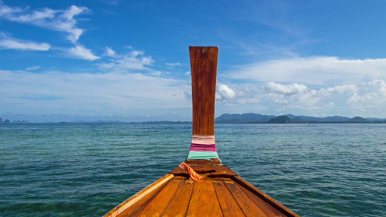 Ein Longtailboot auf dem Weg nach Koh Ngai kann man sich von den leuchtenden Farben des Meeres in den Bann ziehen lassen und die Aussicht, wie auf einem Postkartenmotiv genießen.