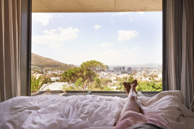 Woman lying in bed looking at nature view in front of her.