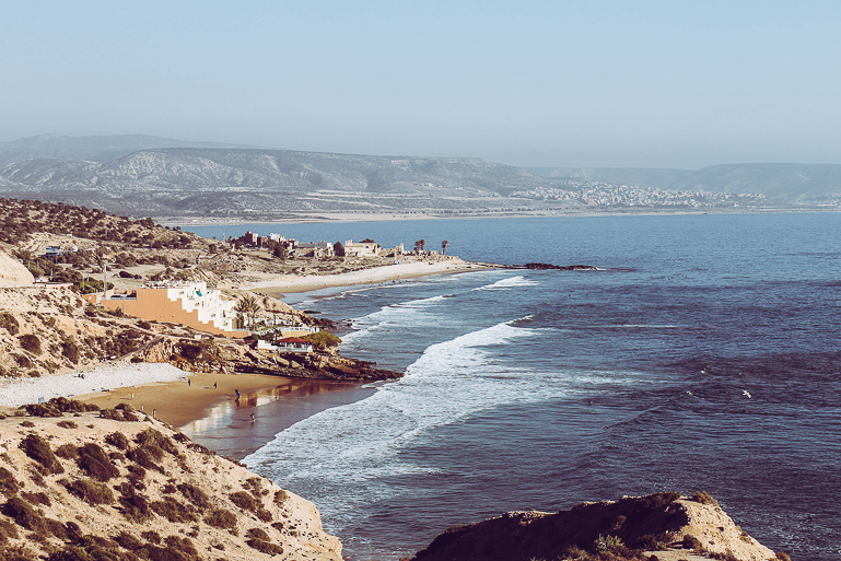 On Morocco's coast near Taghazout, water sports enthusiasts can be seen on the sandy beach.