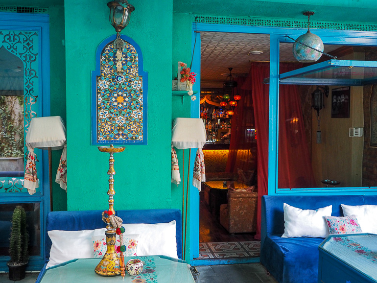 In einem in blau und türkisfarbenen Cafe in Tiflis im Stadtteil Oberes Kala steht auf einem Tischchen vor einer Samtcouch eine Shisha.