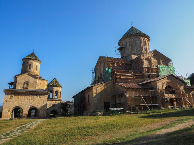 Die steinerne Klosteranlage Gelati mit seinen runden Türmchen in Georgien ist in ein Gerüst zur Renovierung gehüllt.