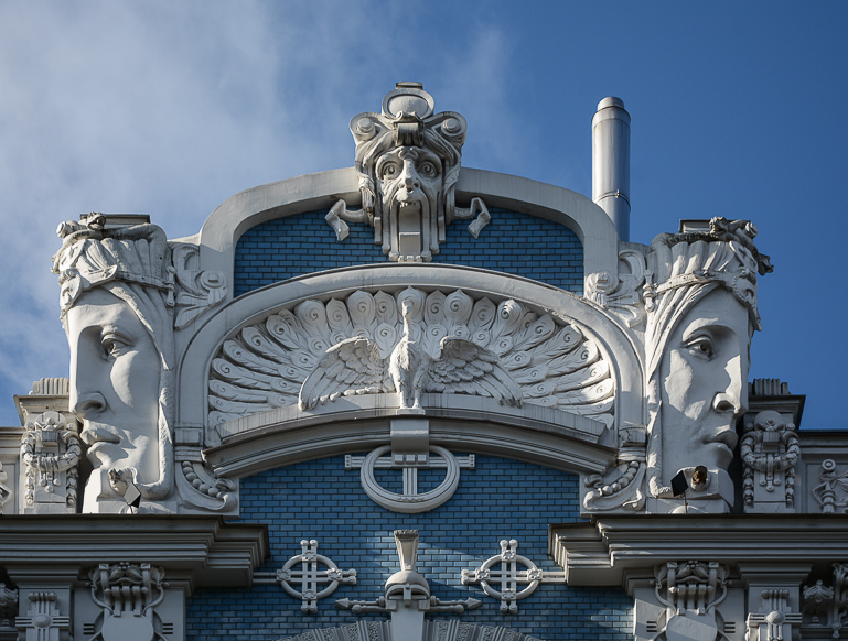 Die im elektischen Jugendstil gehaltene Fassade eines Gebäudes in Riga, Lettland - gesättigt von Dekorationen, Linien, stilisierten Ornamenten und Masken.