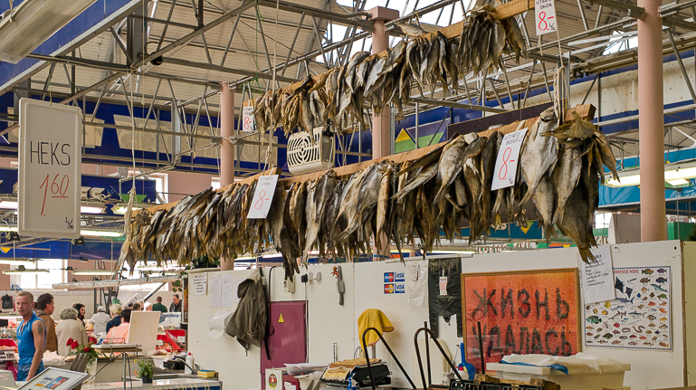 In Rigas Zentralmarkt werden in der Fischhalle getrocknete Heringe aufgereiht auf langen Holzbalken zum Verkauf angeboten.