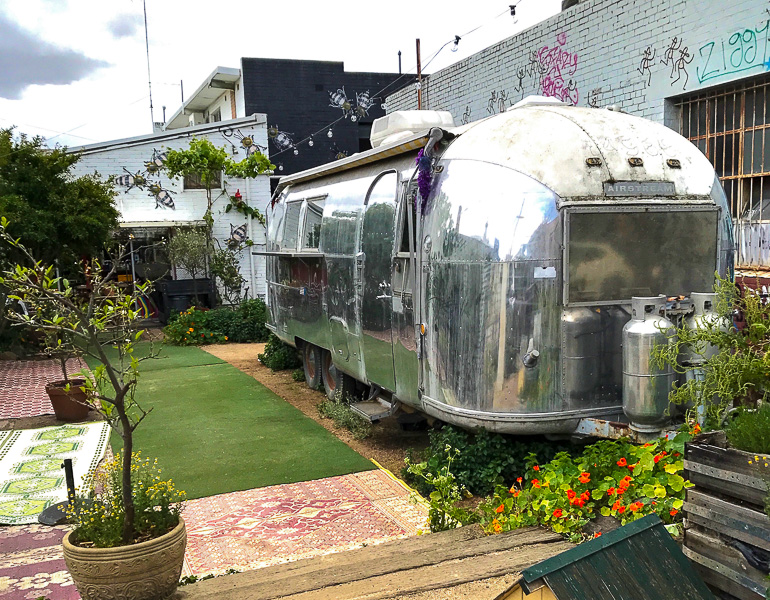 In Victoria, Australien steht ein silberner Camper als Café in Melbournes Viertel Fitroy in einem kleinen begrünten Vorgarten.