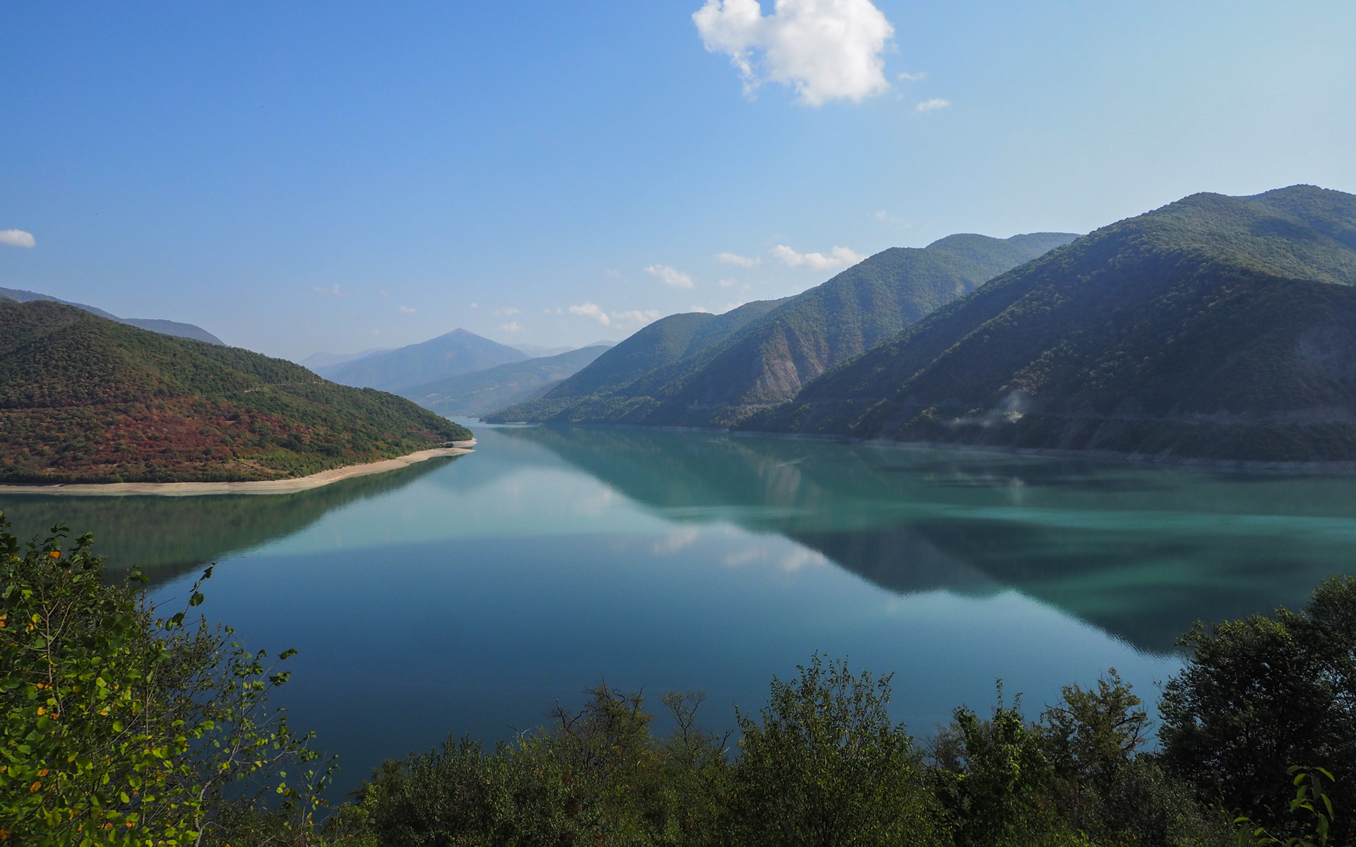 Die tiefblaue Farbe des Jinvali-Stausees begeistert Reisende auf ihrer Route durch Georgien.