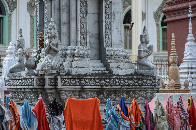 Die Stupas der steinernen Buddha Statue des Wat Dum Rey Sor in Battambang sind mit Wäschestücken zum Trocknen behängt.
