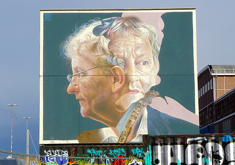 Auf einer großen Plattform im Hipsterviertel in Amsterdam ist ein großes Bild mit zwei Köpfen gezeichnet.
