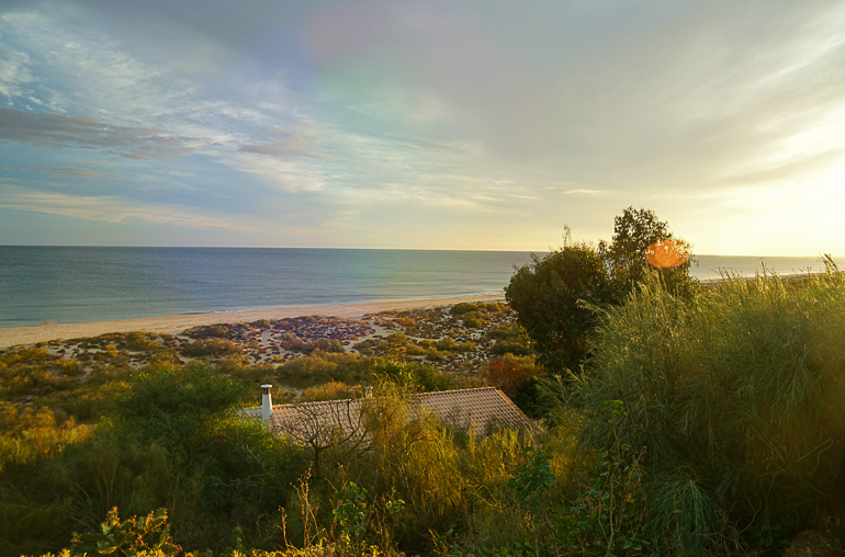 Die Abendsonne taucht den menschenleeren Strand an der Algarve in Portugal in ein warmes Licht.