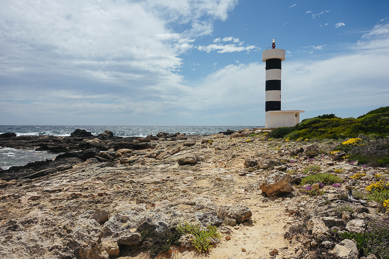 Der schwarz-weiß gestreifte Leuchtturm s’Estanyol steht in Mallorca am Ufer des Meeres.
