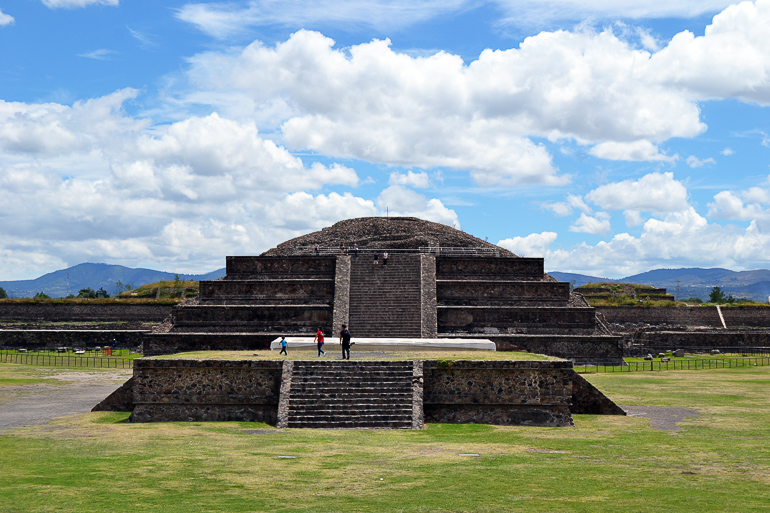 Eine steinerne Pyramide mit vielen Treppen auf einer Wiese in Teotihuacan, Mexiko.