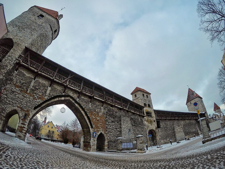 Durch den großen Torbogen der alten Stadtmauer von Estlands Hauptstadt Tallinn führt eine Straße, die drei Wachtürme erinnern an die vergangene Zeit.