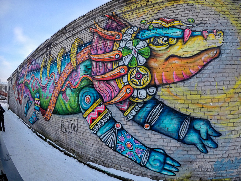 Im Viertel von Kalamaja in Tallinn ist auf einem hohen Mauervorsprung ein bunter Drache als Graffiti zu sehen.