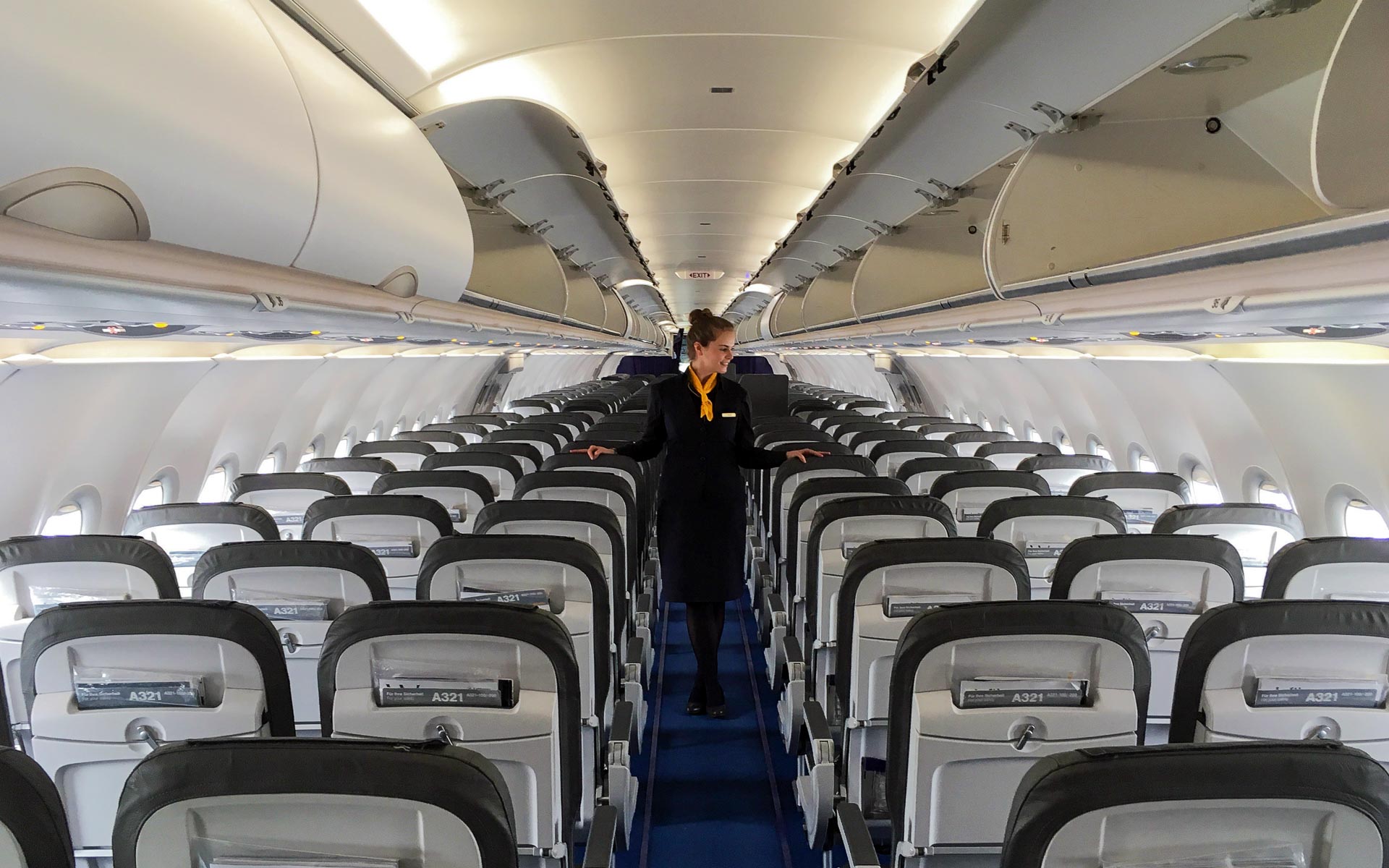 Eine Stewardess geht durch den Flur eines Flugzeuges und überprüft die Sitzreihen.