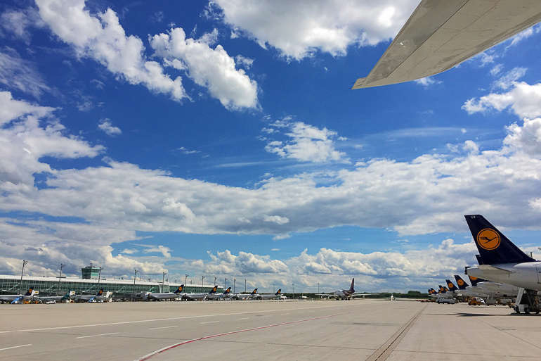 Unter blauweißem Himmel parken die Flugzeuge auf dem Vorfeld des Flughafens München.