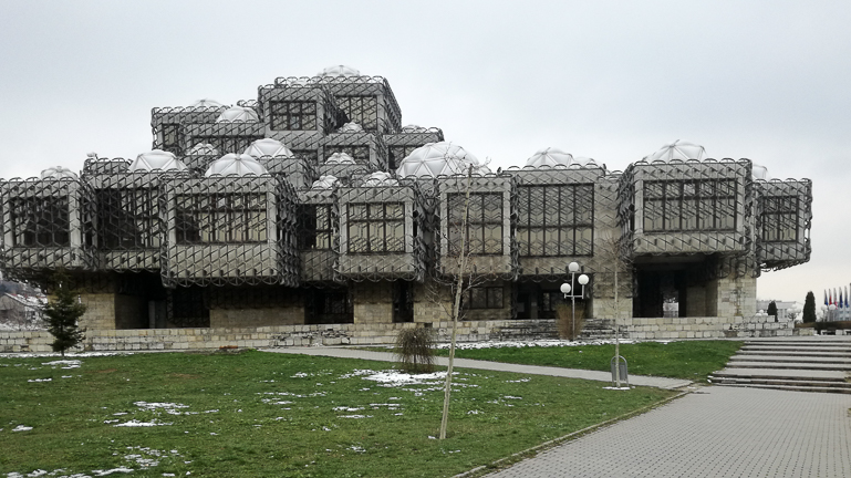 Bei einem Besuch in Pristina, Kosovo, sollte die Nationalbibliothek nicht fehlen, die mit ihrem Erscheinungsbild - zu dem 99 weiße, gläserne Kuppeln und großen gitterartige Metallnetze zählen - kontrovers diskutiert wird.