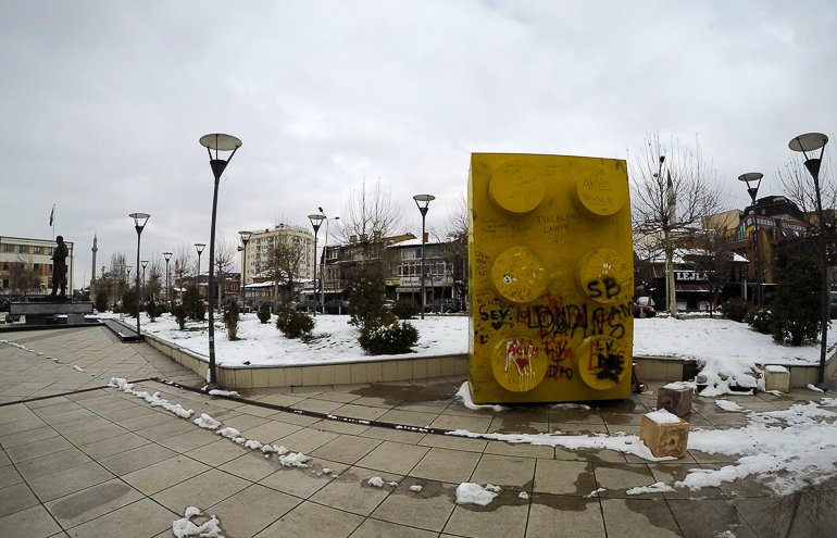 Das mit Graffiti beschmierte Wahrzeichen, ein gelber großer Legostein, in Pristina, Kosovo, steht für die sechs Regionen des Kosovos und soll als fehlendes Puzzle- beziehungsweise Lego-Stück der EU repräsentieren.