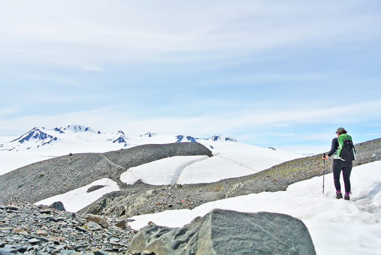 A female ski tourer hikes snow-capped rock mountains on Alaska's Kenai Peninsula.