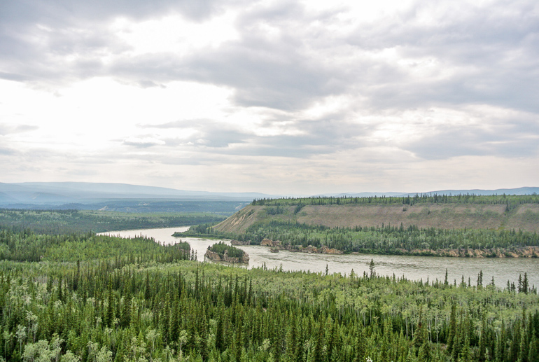 In Alaska on the Five Finger Rapids on the Yukon River lie forested hills along the river.