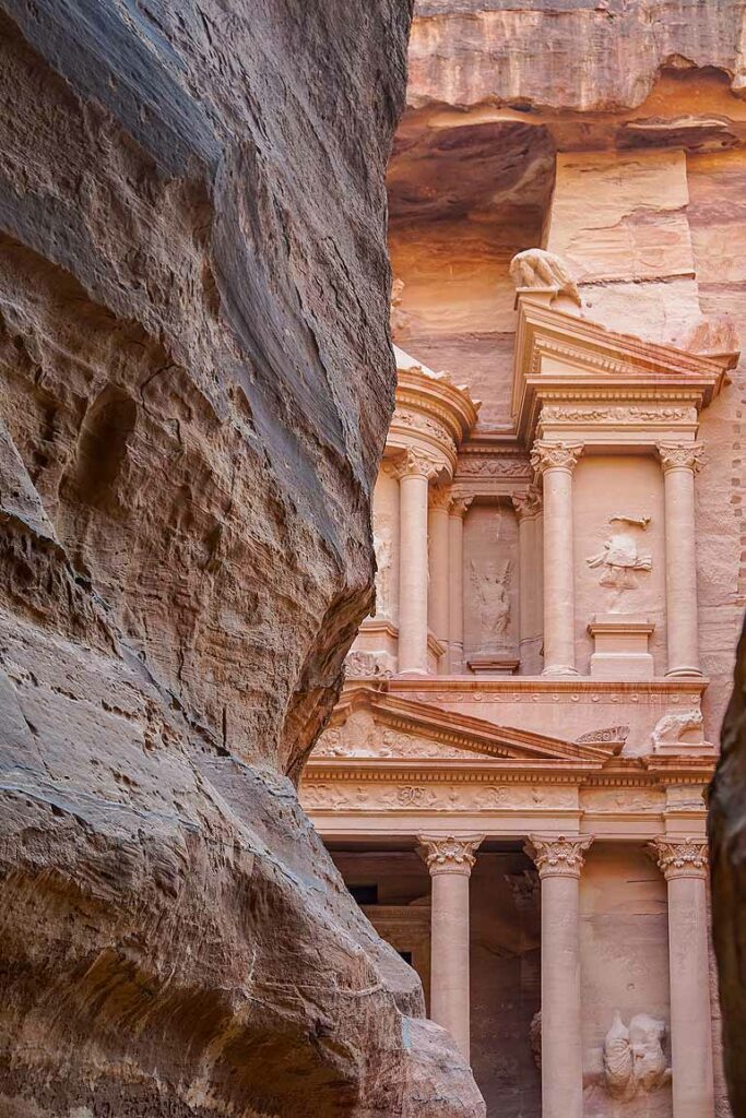 Hinter einem Felsen erstrahlt die Fassade der Schatzkammer Petras in Jordanien.