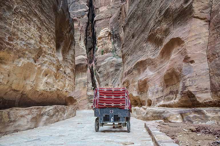 Eine alte Kutsche fährt durch die enge Gasse des Siq Canyons, Petra in Jordanien.