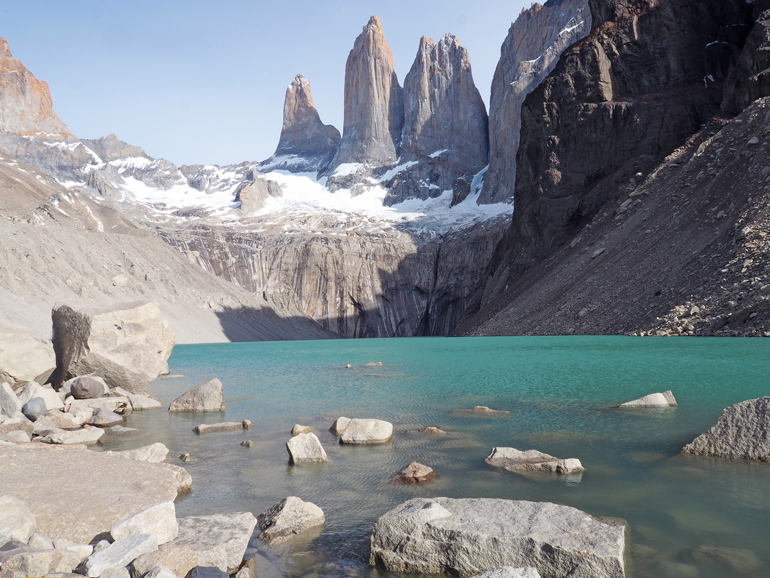 The view of the Torres del Paine shows turquoise waters and steep rocky peaks.
