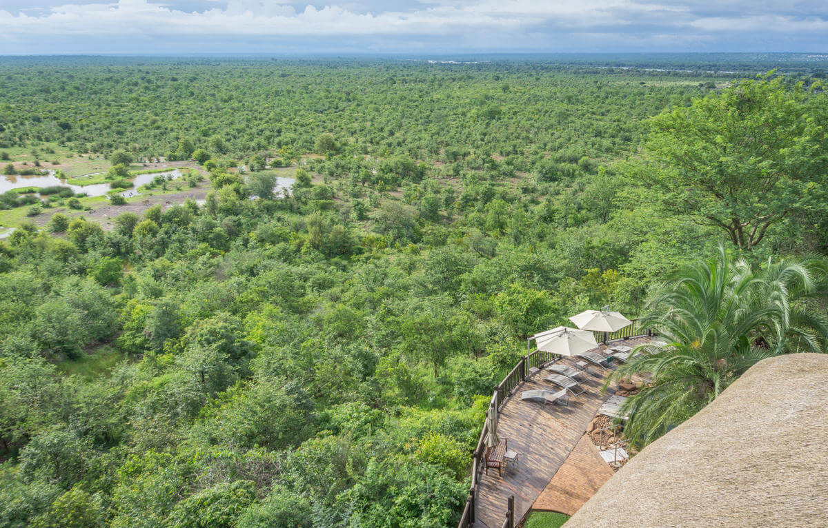 Blick von oben auf die Sonnenterrasse der Victoria Falls Safari Lodge und die grüne Natur in der Umgebung.