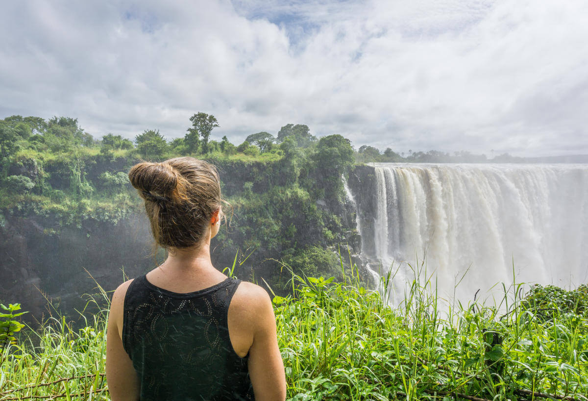 A woman in a black top and bun has her eyes on Zimbabwe's Victoria Falls.