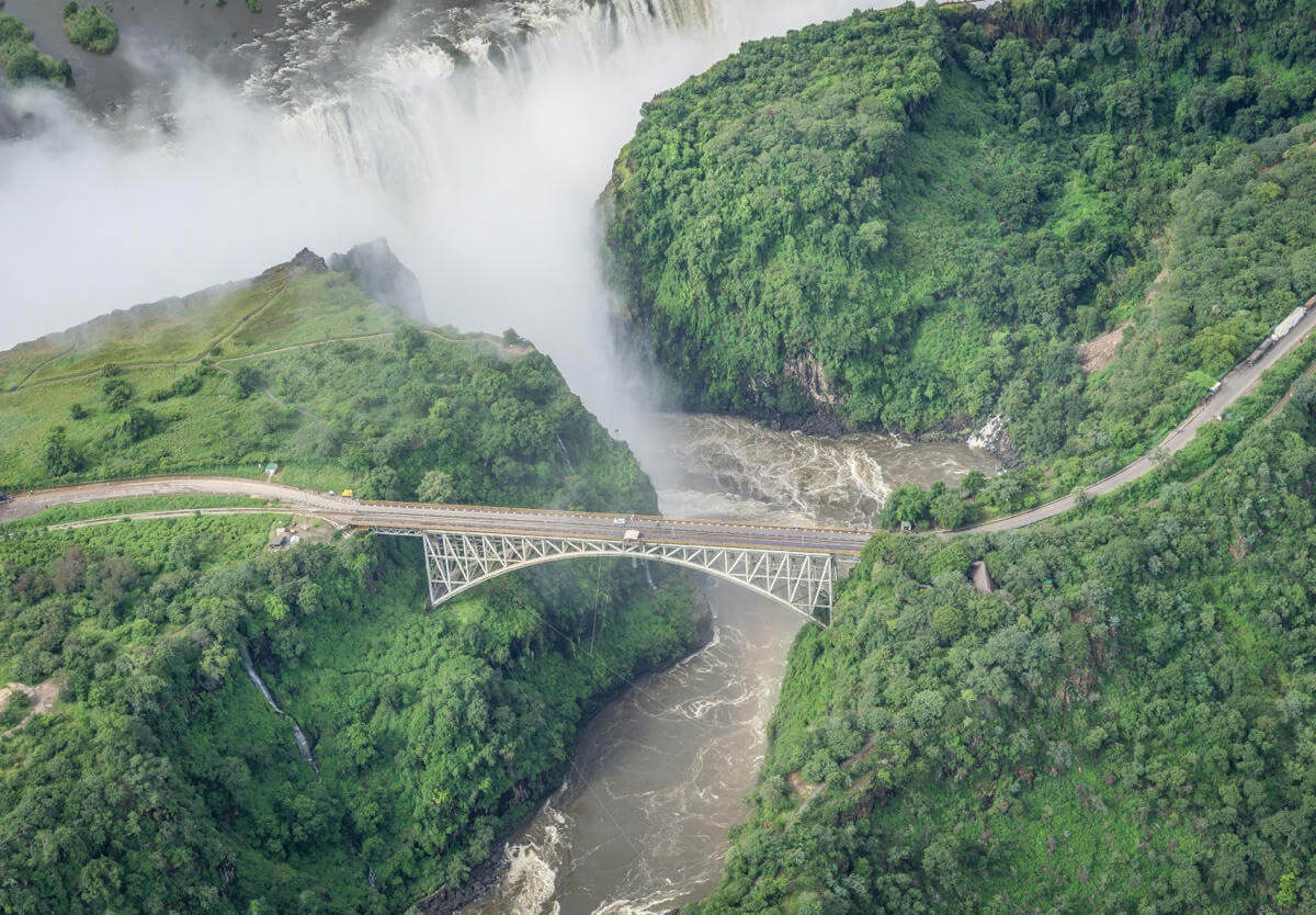 The historic Victoria Falls Bridge near the falls and its lush vegetation from above.