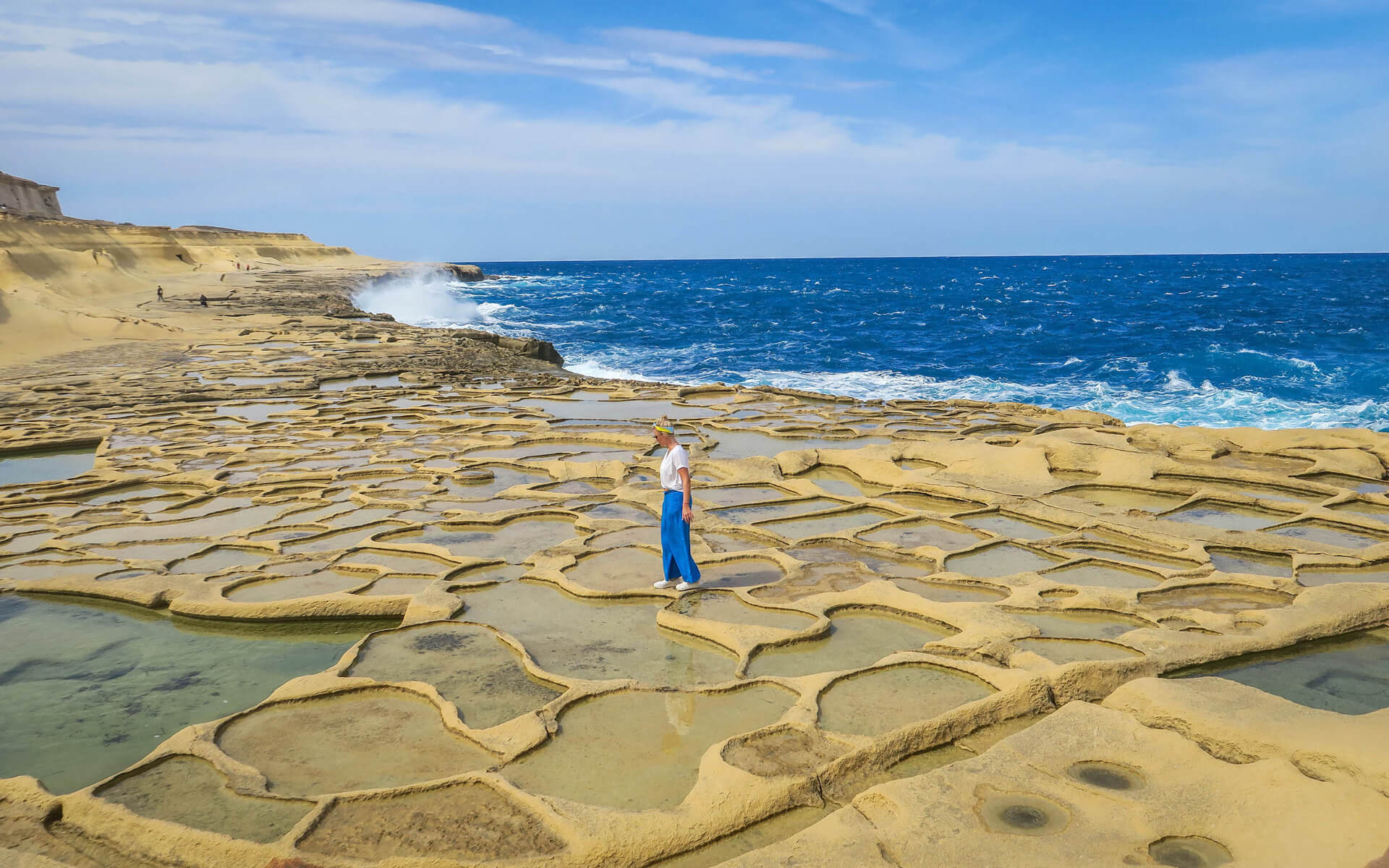 Frau läuft über die mit Meerwasser gefüllten Salzpfannen von Gozo.