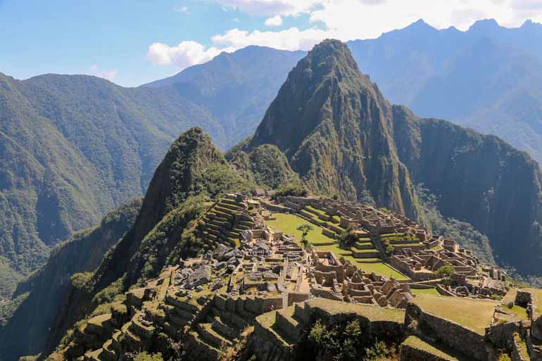 Ausblick auf den Machu Picchu mit Mauern im Vordergrund.
