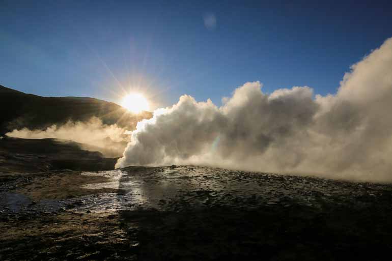 At sunset, a cloud of white steam rises from a crevasse in the El Tatio geyser field in Bolivia.