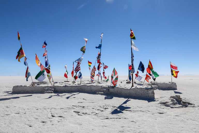 In den scheinbar endlosen Weiten der Salar de Uyuni wurden viele verschiedene Flaggen auf einem Stein befestigt.