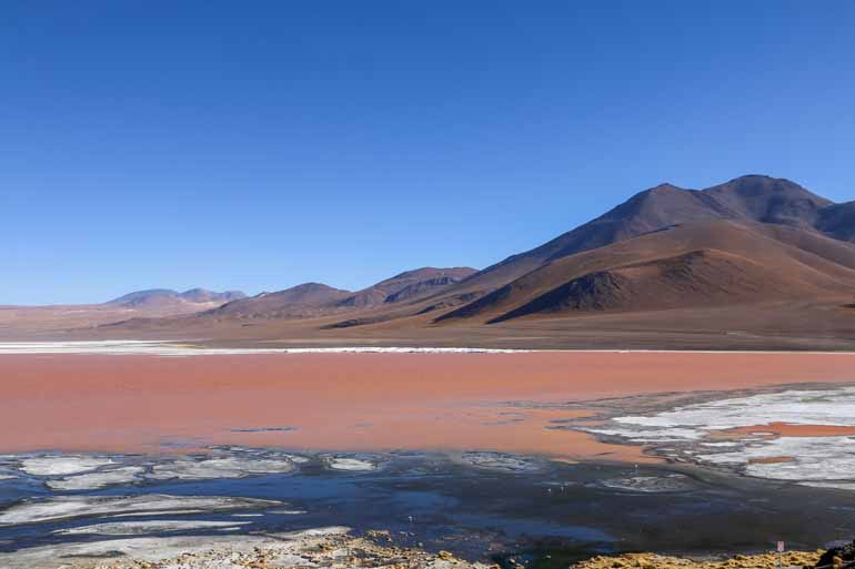 The Laguna Colorada in Bolivia rightly bears its name with its red water and its mountains in the background.