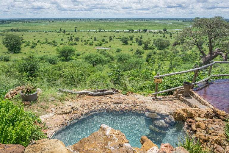 Ein Pool auf einer Erhöhung im Hintergrund der herrliche Ausblick auf die Landschaft des Chobe Nationalpark in Botswana.