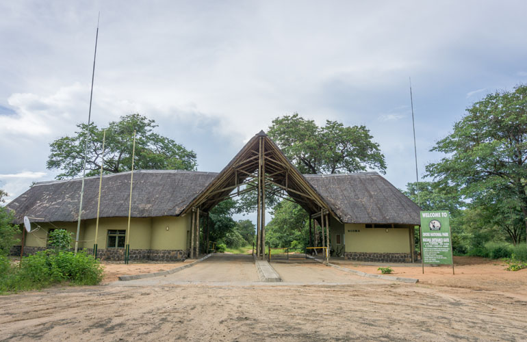 Das Eingangsgebäude des Chobe Nationalparks mit seinem Schindeldach mit Holz und hellgrün gehalten.