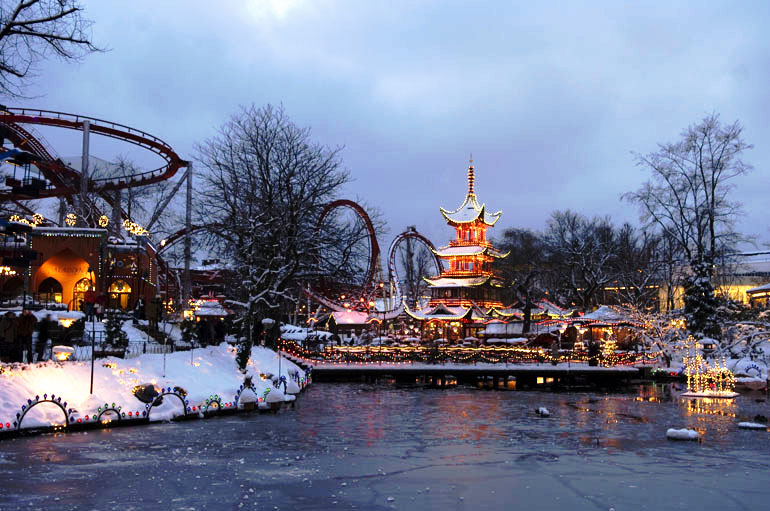Weihnachtsmarkt hinter einem See, dahinter eine Achterbahn