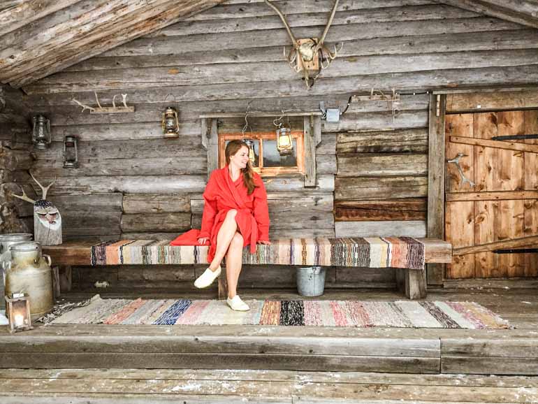 Frau sitzt vor einer Sauna Hütte in Finnisch Lappland.