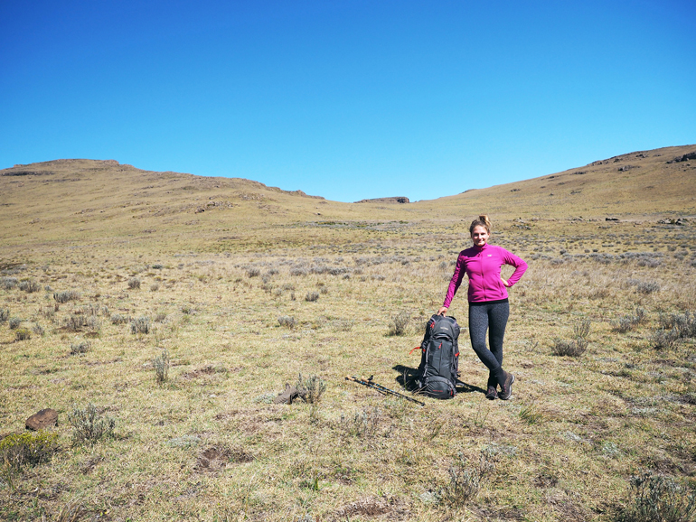 Südafrika Drakensberge: Eine Frau mit Rucksack lächelt in die Kamera.