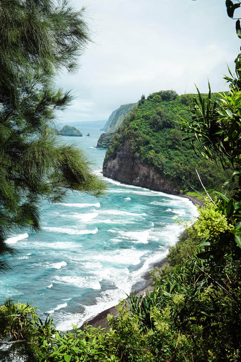 The black sands of Pololu Valley on Bis Island are surrounded by green rocky landscapes.