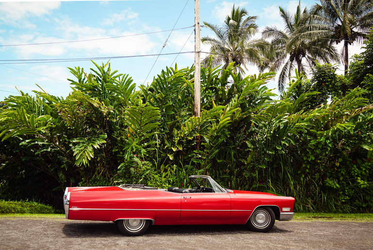 The best way to explore Hawaii's palm-lined streets is in a red vintage convertible.
