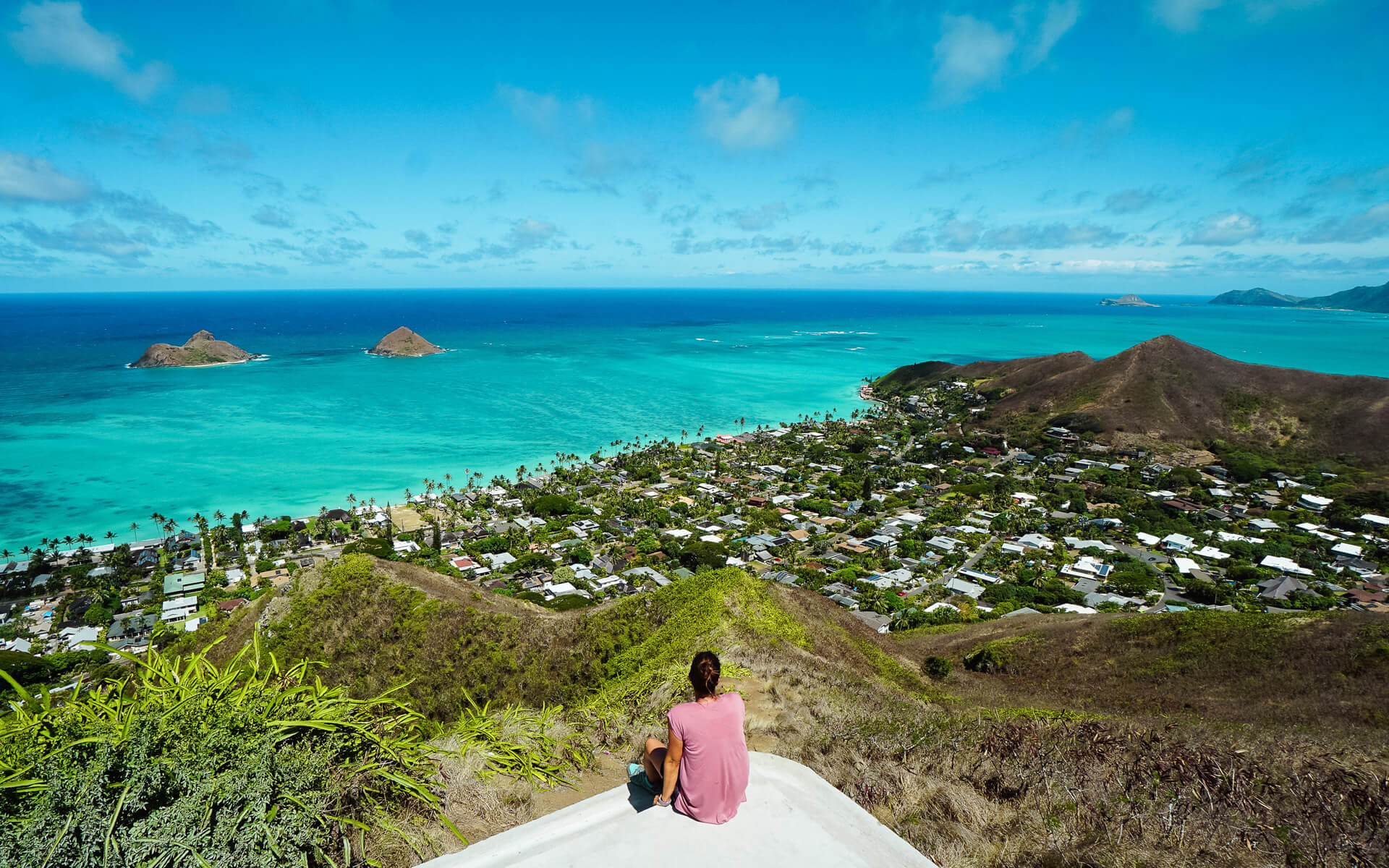 Ein sagenhaften Rundumblick über Hawaii und dem Lanikai Beach erwartet einem auf dem Emde des Pillbox Hike, kleine Hütten zieren in grüner Vegetation die Landschaft und das azurfarbene Meer verschmilzt am Horizont mit dem Himmel.