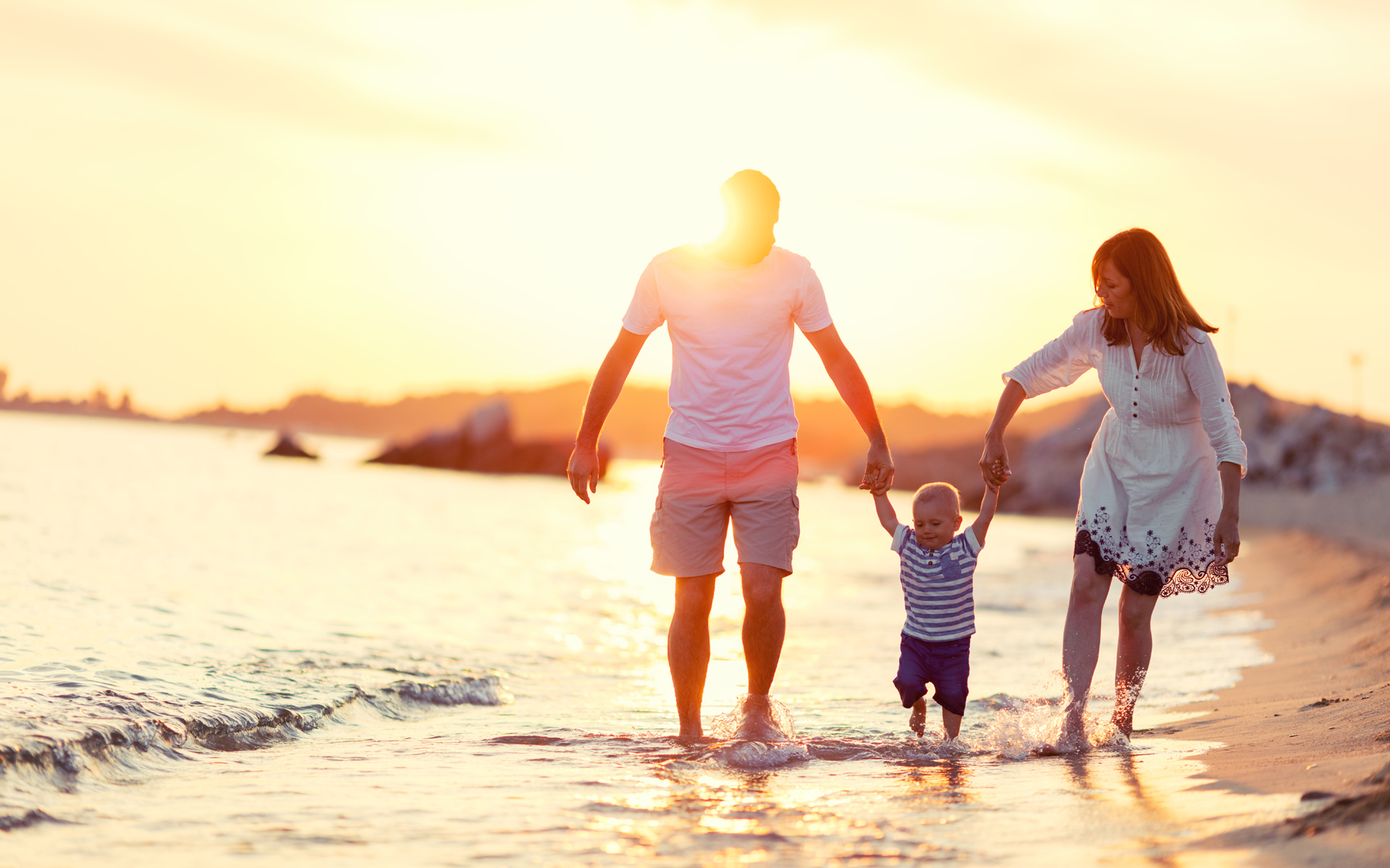 Elternzeit Reisen: Mutter und Vater mit Baby am Strand