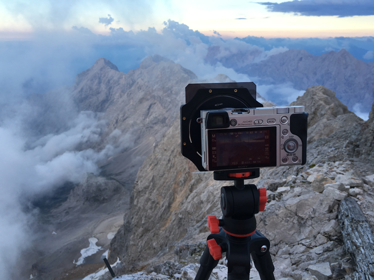Beste Reisekamera: Eine Kamera steht auf einem Stativ mit Blick auf die Berge.