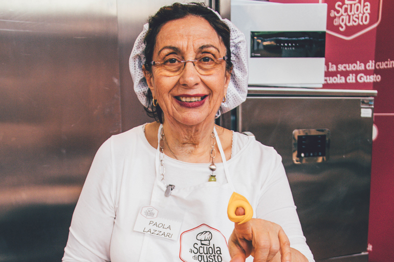 Paola Lazzari, Pastakönigin von Bologna, hält in der Scuola di Gusto eine Tortellini in die Kamera.
