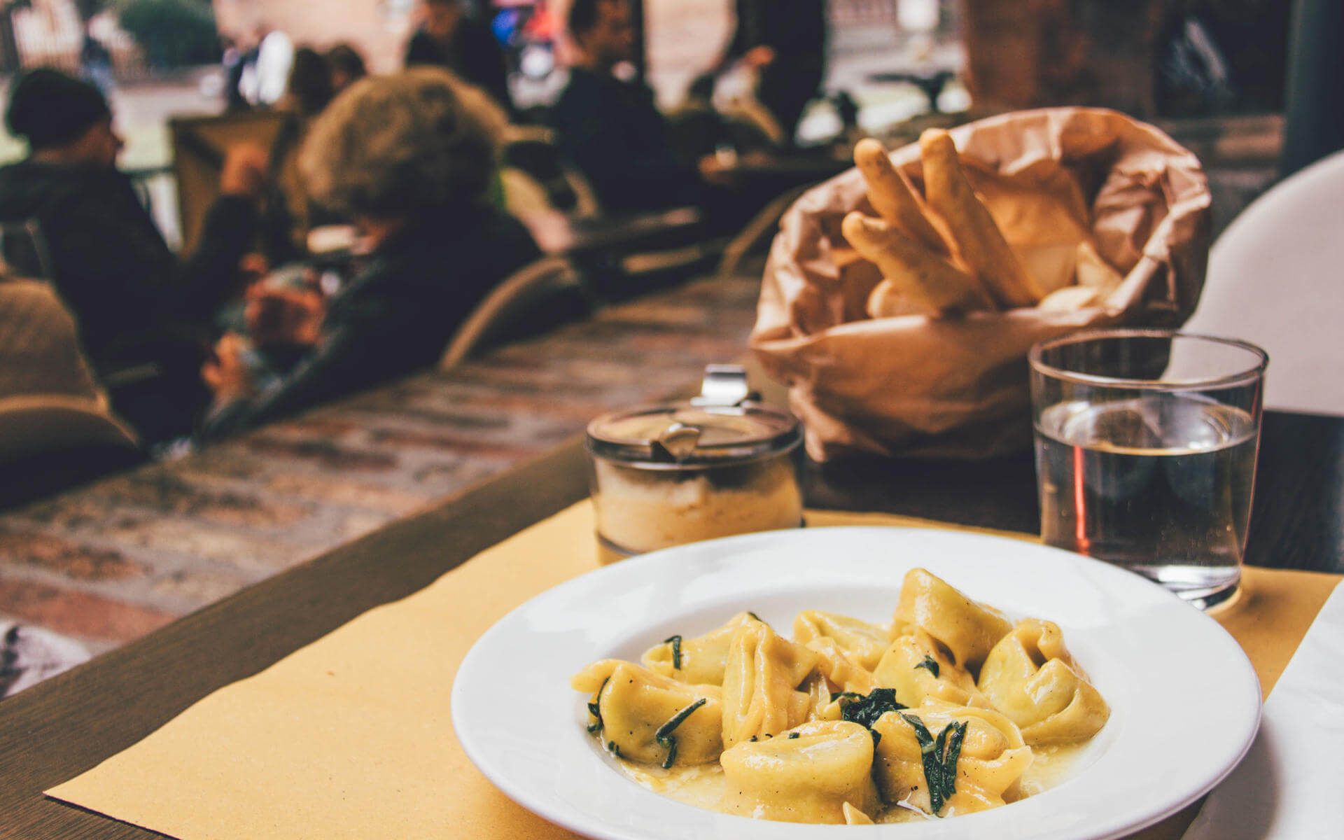 Tipp für Essen in Bologna: Ein angerichteter Teller mit Tortellini auf einem gedecktem Tisch.