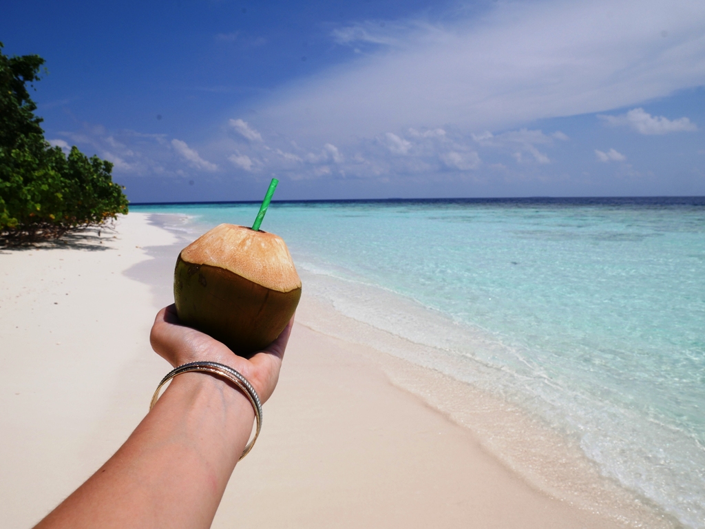 Sich auf Reisen allein einmal so richtig verwöhnen - zum Beispiel mit einem Strohhalm in der Kokosnuss am Strand.